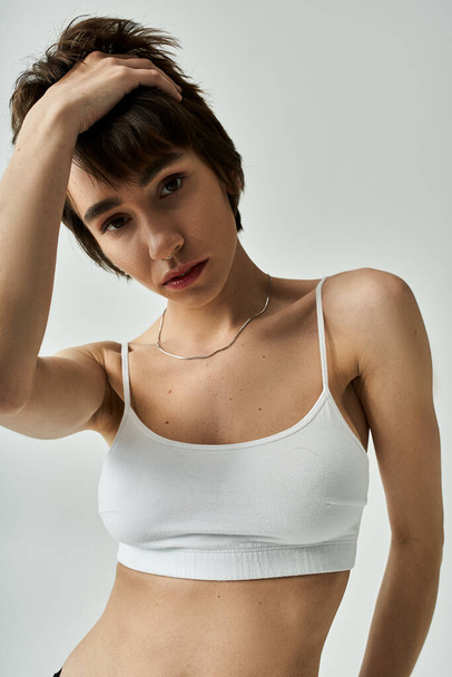 Stylish, active young woman wearing white sports bra and black shorts. - Foto, Imagem