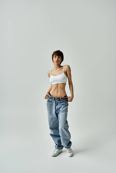Beautiful young woman posing gracefully in jeans and a white tank top. - Foto, Imagem