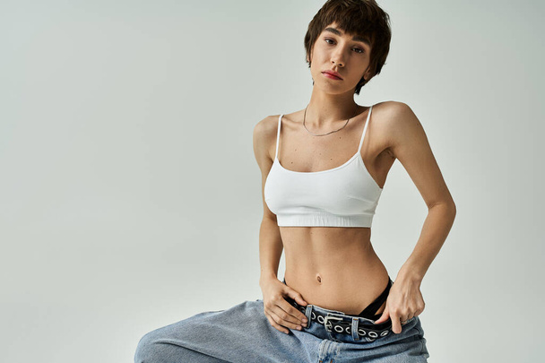 A stylish young woman posing confidently in jeans and a white top. - Photo, image
