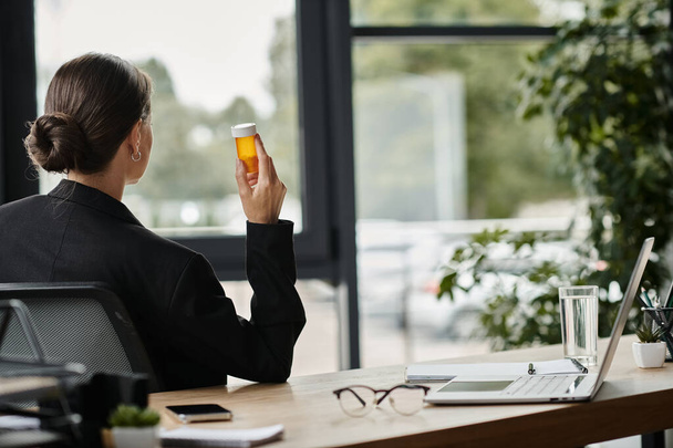 Middle-aged woman in a business suit holding a bottle of medicine. - Fotó, kép