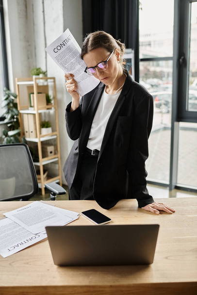 Stressed middle-aged woman in business suit sits at desk with papers. - Foto, Imagem