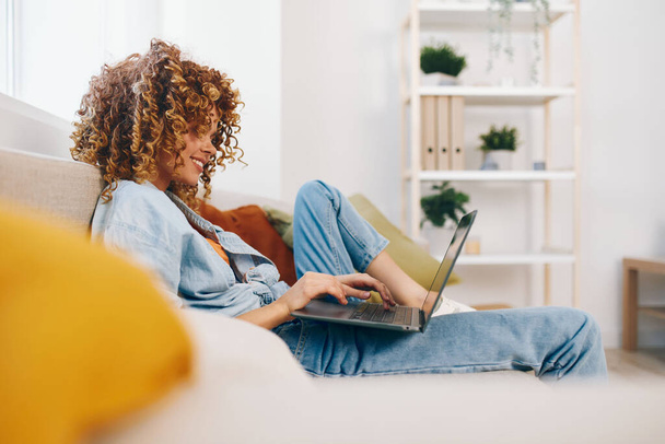 Femme souriante travaillant sur ordinateur portable à la maison : style de vie moderne et succès freelance. - Photo, image