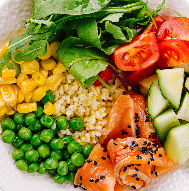 Vista superior de un colorido poke bowl con salmón ahumado, verduras y arroz - Foto, imagen