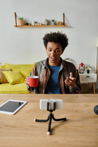 Young African American male blogger chatting on phone camera while savoring a cup of coffee. - Foto, imagen