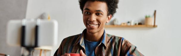 Young man, smiling, holds coffee cup. - Φωτογραφία, εικόνα