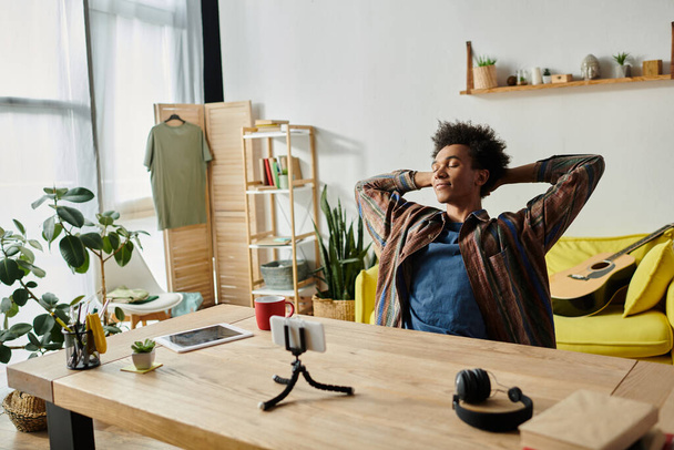 Young African American male blogger sitting at desk, hands on head, deep in thought. - Foto, imagen