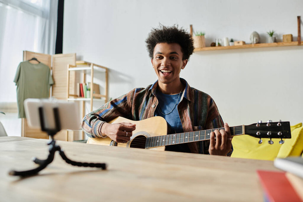 Young man playing acoustic guitar in cozy living room. - Fotó, kép