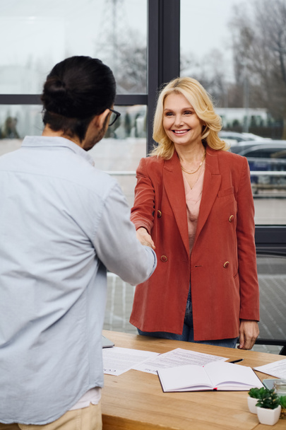 Une femme et un homme se serrent la main dans un bureau lors d'un entretien d'embauche. - Photo, image