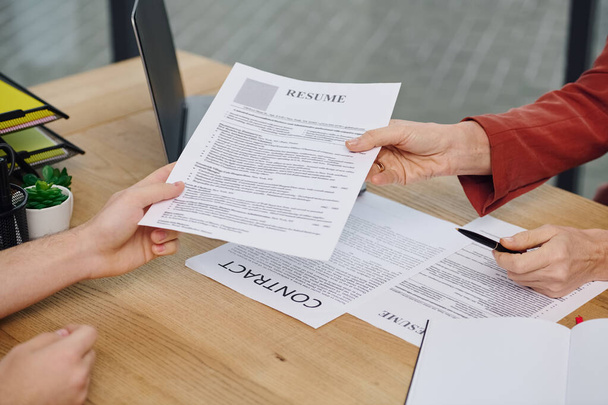 A man hands a resume to a woman during a job interview. - Photo, Image