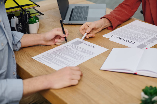 Dos personas en una mesa, firmando un documento durante una entrevista de trabajo. - Foto, imagen