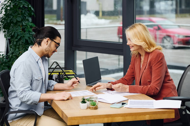 Een man en vrouw voeren een sollicitatiegesprek aan een tafel in een kantoor. - Foto, afbeelding