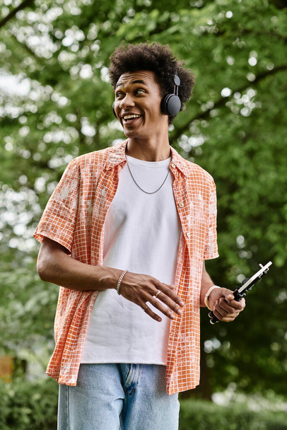 A young man with headphones walks in the park. - Foto, Imagen