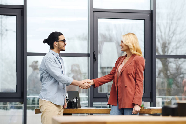 A man and woman shaking hands in an office setting. - Photo, Image
