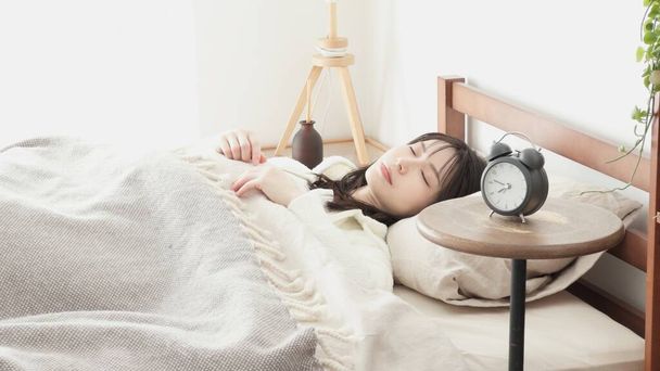 Mujer poniendo un despertador y yendo a dormir - Foto, imagen