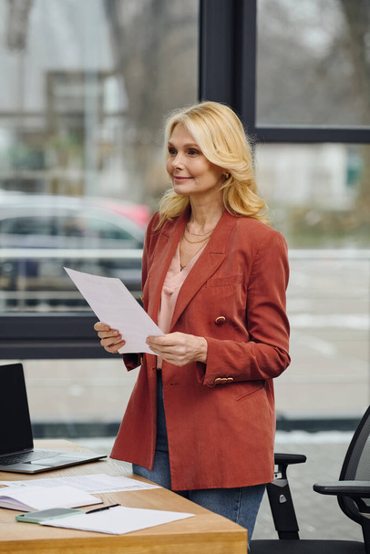 Une femme se tient à un bureau, tenant un papier. - Photo, image