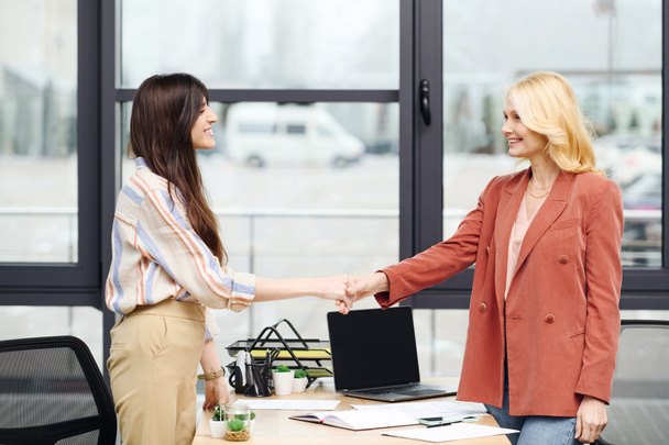 Two women shaking hands in an office setting. - Photo, Image