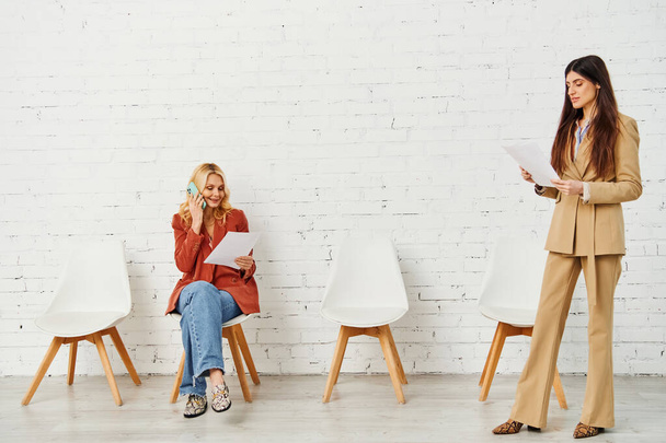 椅子に座っている間に会話に従事する2人の女性. - 写真・画像