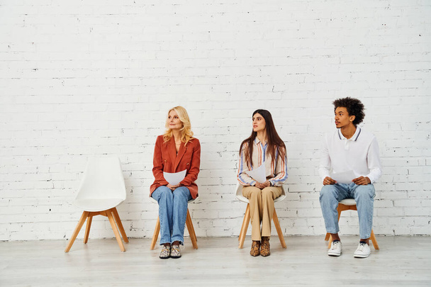 Οι άνθρωποι κάθονται σε καρέκλες μπροστά από ένα απλό λευκό τοίχο. - Φωτογραφία, εικόνα