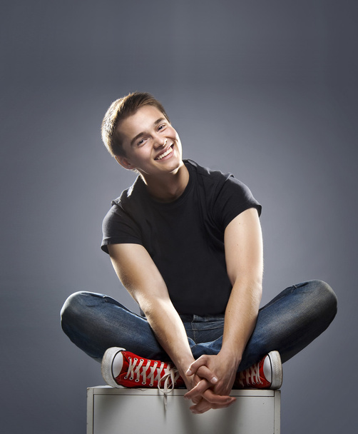 Young casual happy man sitting with crossed legs and hands - Foto, Imagen