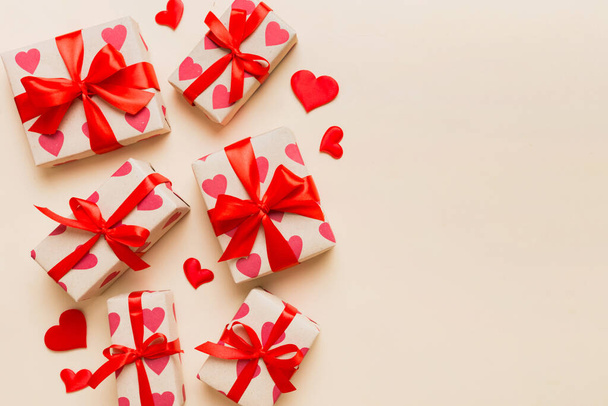 Top view photo of valentine day decorations gift box with red ribbon bow on colored background. Holiday gift boxes with top view. - Φωτογραφία, εικόνα