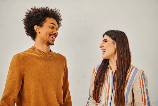 Hombre y mujer se ríen felizmente frente a un telón de fondo llano. - Foto, Imagen