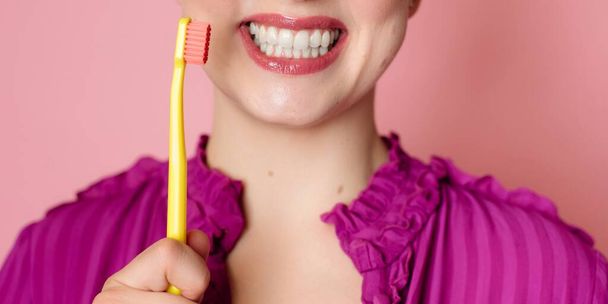 Close-up de um sorriso branco de neve de mulheres. Próximo a ele é uma escova de dentes em uma mão de mulheres. bandeira panorâmica - Foto, Imagem