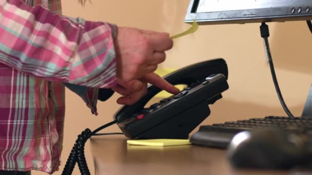 粘着性があるノート メッセージが付いているオフィスの電話の手のダイヤル番号4kショットの遅い動き選択的な焦点 - 映像、動画