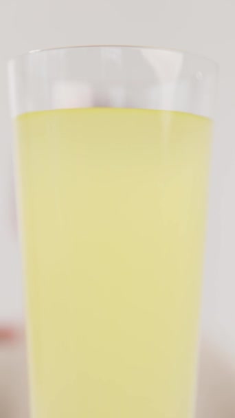 Vertical video. The silhouette of a blurred boy takes a glass of lemon and lime juice with two hands, close-up. The concept of natural lemonade for childrens health. - Footage, Video