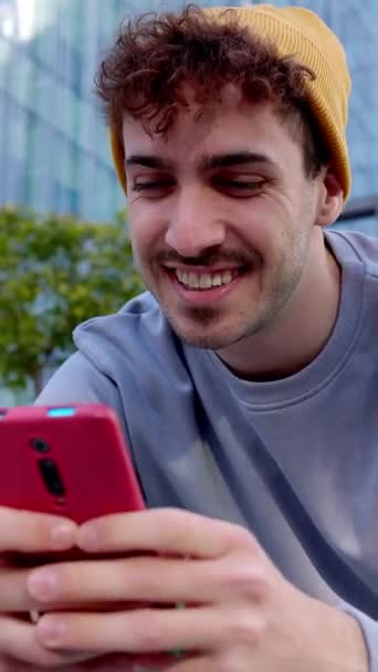 Κάθετη HD βίντεο του νέου hipster άνθρωπος χρησιμοποιώντας το κινητό τηλέφωνο κάθεται σε ποδήλατο στο κολέγιο πανεπιστημιούπολη. Τεχνολογικός τρόπος ζωής και έννοια των μέσων κοινωνικής δικτύωσης. - Πλάνα, βίντεο