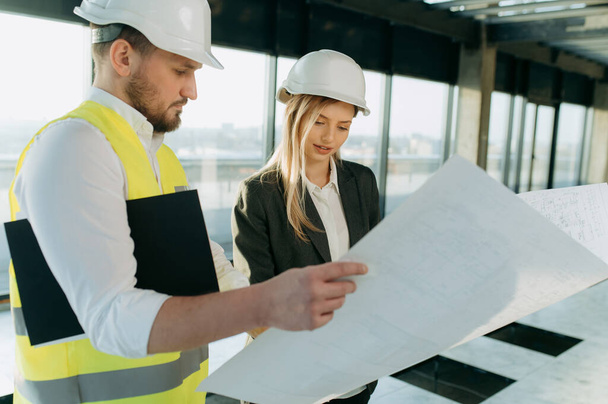 architect, designer, engineer examine the project on paper. A business woman and an architect are talking about a project in an office interior - Photo, Image