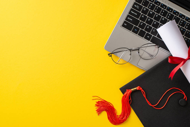 Fényes képet ábrázoló ballagási sapka és diploma tetején egy laptop, a szemüveg mellett, meg egy élénk sárga háttér szimbolizálja teljesítmény az online oktatás - Fotó, kép
