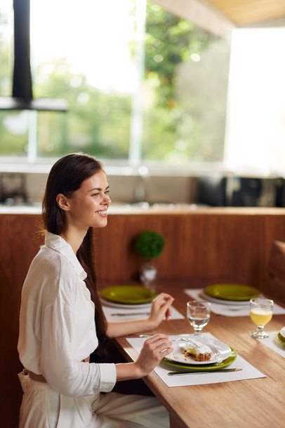 Glückliche Frau genießt ein romantisches Abendessen zu Hause mit leckerem Kuchen und Wein - Foto, Bild