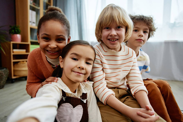 Diverso grupo de niños pequeños tomando foto selfie y sonriendo a la cámara en la clase preescolar o jardín de infantes - Foto, imagen