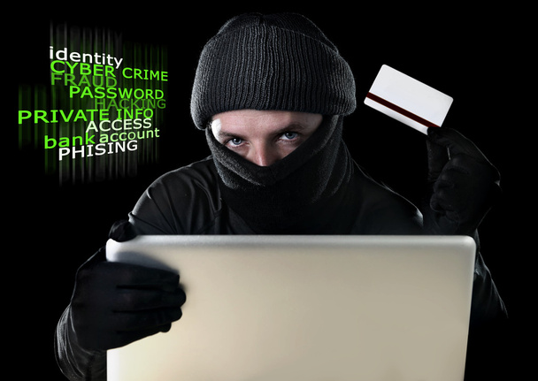 man in zwarte bedrijf creditcard met behulp van computer laptop voor criminele activiteiten hacking wachtwoord en soldaat wetenswaardigheid - Foto, afbeelding