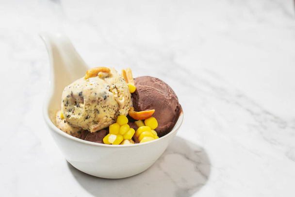 Helado de vainilla y helado de chocolate cubierto con maíz en un tazón sobre una mesa de mármol. Helado casero - Foto, imagen
