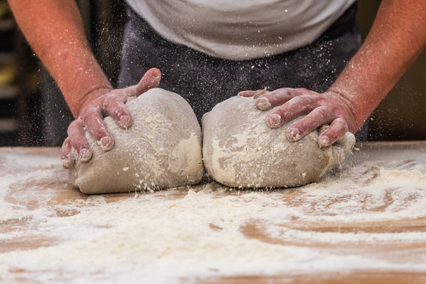 Um padeiro amassa massa de pão na padaria.  - Foto, Imagem