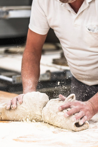 Um padeiro amassa a massa de pão na padaria. Vertical. - Foto, Imagem