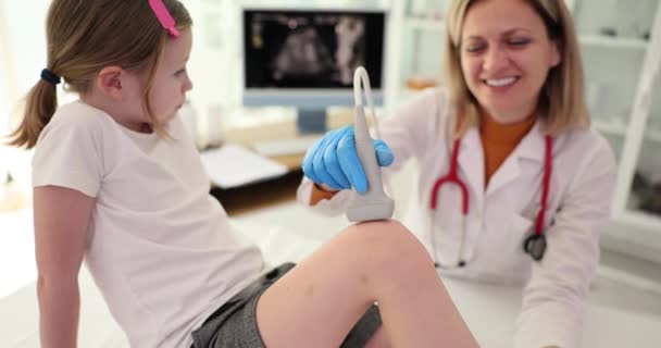 Lekarz traumatolog przeprowadza badanie ultrasonograficzne kolana dziecka w klinice. Ból stawów i łąkotki u dzieci - Materiał filmowy, wideo