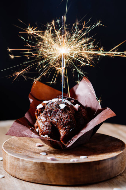 Festive chocolate muffin with sparkler on a dark background. - Foto, imagen