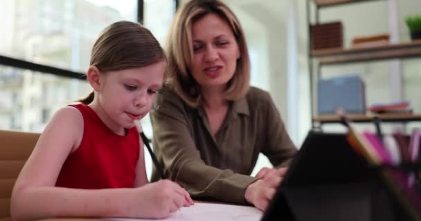 Jonge moeder doet huiswerk samen met haar dochter thuis. Repeater vrouw doet huiswerk met meisje - Video