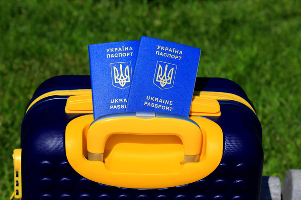 2 passaporti cittadini ucraini con iscrizione in ucraino Passaporto dell'Ucraina si trovano sulla valigia gialla blu a colori della bandiera ucraina. Viaggi, rifugiati, turismo, emigrazione, mobilitazione, migranti - Foto, immagini