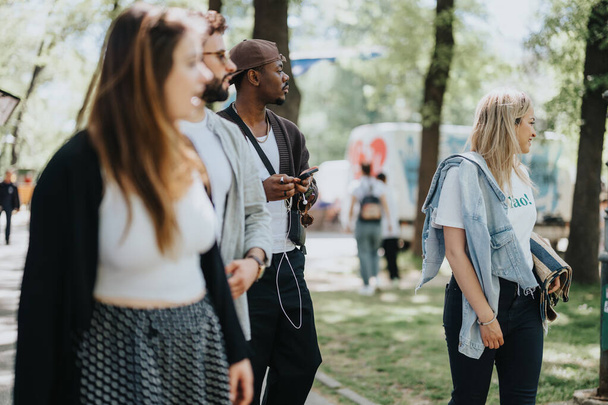 Eine multiethnische Gruppe von Freunden spaziert an einem sonnigen Tag im Stadtpark zusammen im Freien und teilt Freude und Lachen in ihrer Freizeit. - Foto, Bild