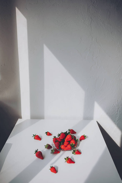Sommer Hintergrund mit Erdbeeren auf weißem Tisch. Heller Hintergrund mit Schatten vom Fenster, mit Kopierraum. - Foto, Bild