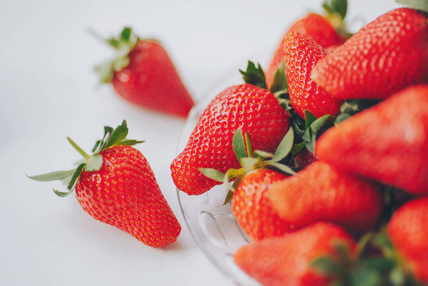 Κλειστό από φρέσκια φράουλα. Κόκκινες φράουλες σε ένα μπολ έτοιμες να φάνε. Φράουλες σε σωρούς σε λευκό γυάλινο πιάτο.  - Φωτογραφία, εικόνα