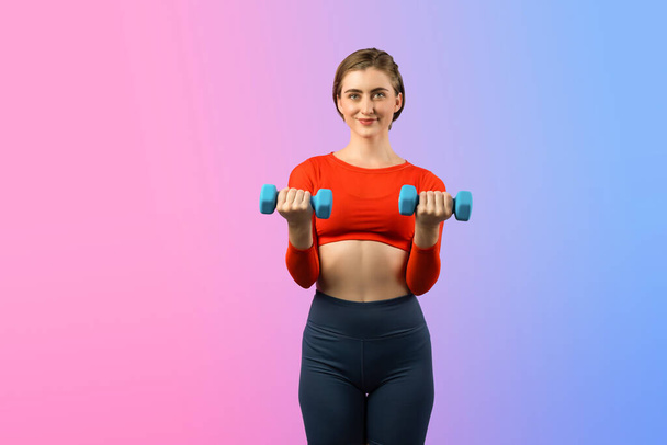 ボディービルの練習として重量を持ち上げるためのダンベルが付いている全身の長さのガンジーショット運動およびスポーティな女性隔離された背景の立っている姿勢で. 健康的なアクティブでボディケアライフスタイル - 写真・画像