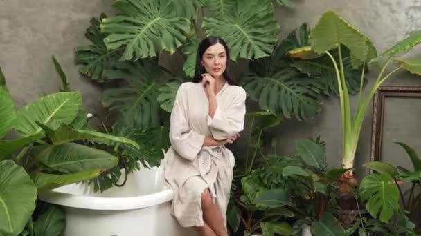 Tropical and exotic spa garden with bathtub in modern hotel or resort with young woman in bathrobe enjoying leisure and wellness lifestyle surrounded by lush greenery foliage background. Blithe - Footage, Video