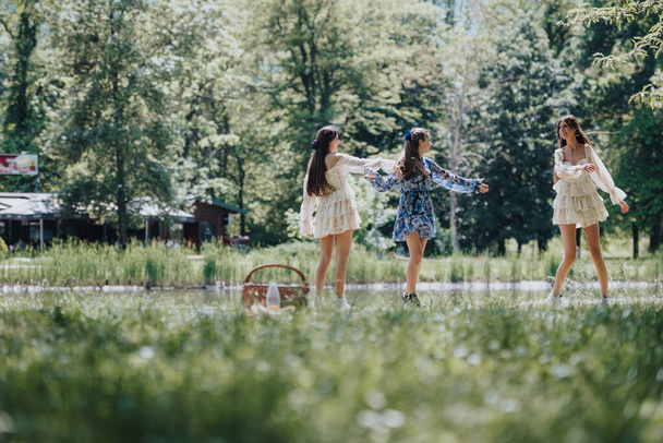 Ξέγνοιαστες και χαρούμενες, τρεις αδελφές χορεύουν σε ένα ηλιόλουστο πάρκο, αναδεικνύοντας την ομορφιά και την ελευθερία μιας τέλειας ανοιξιάτικης μέρας. - Φωτογραφία, εικόνα