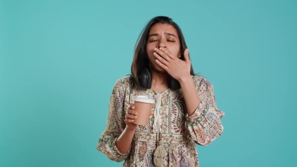 Woman suffering from insomnia yawning, sipping coffee to gain energy and get rid of pain. Tired person feeling drowsy after sleepless night, drinking caffeinated beverage, studio background, camera A - Footage, Video