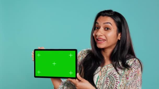 Šťastná žena představuje zelenou obrazovku tablet, izolované přes studio pozadí. Radostná indiánská osoba s kopírovacím prostorovým klíčovým zařízením používaným pro reklamní značky, kamera B - Záběry, video