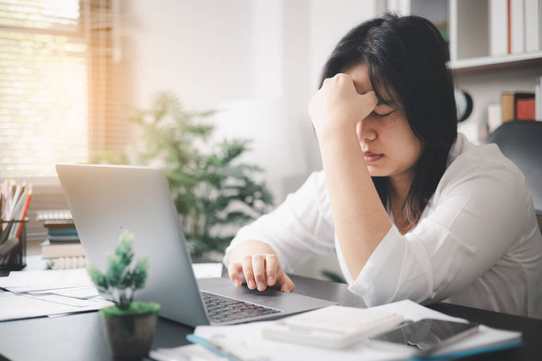 Стрессовая деловая женщина, справляясь с давлением работы и тяжестью депрессии, оказывается в офисе, чувствуя себя сонной и подавленной требованиями своей работы.. - Фото, изображение